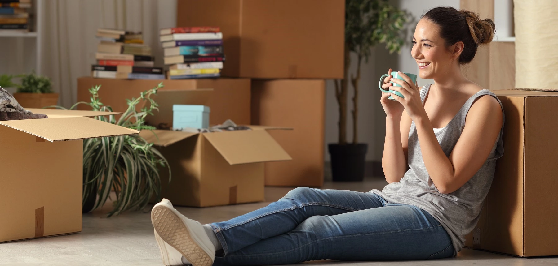 Femme assise contre des cartons de déménagement